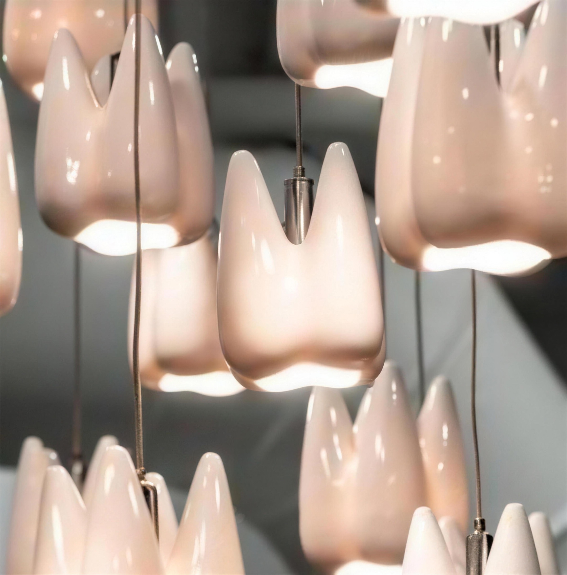 Glossy porcelain tooth-form pendants glowing in a cluster