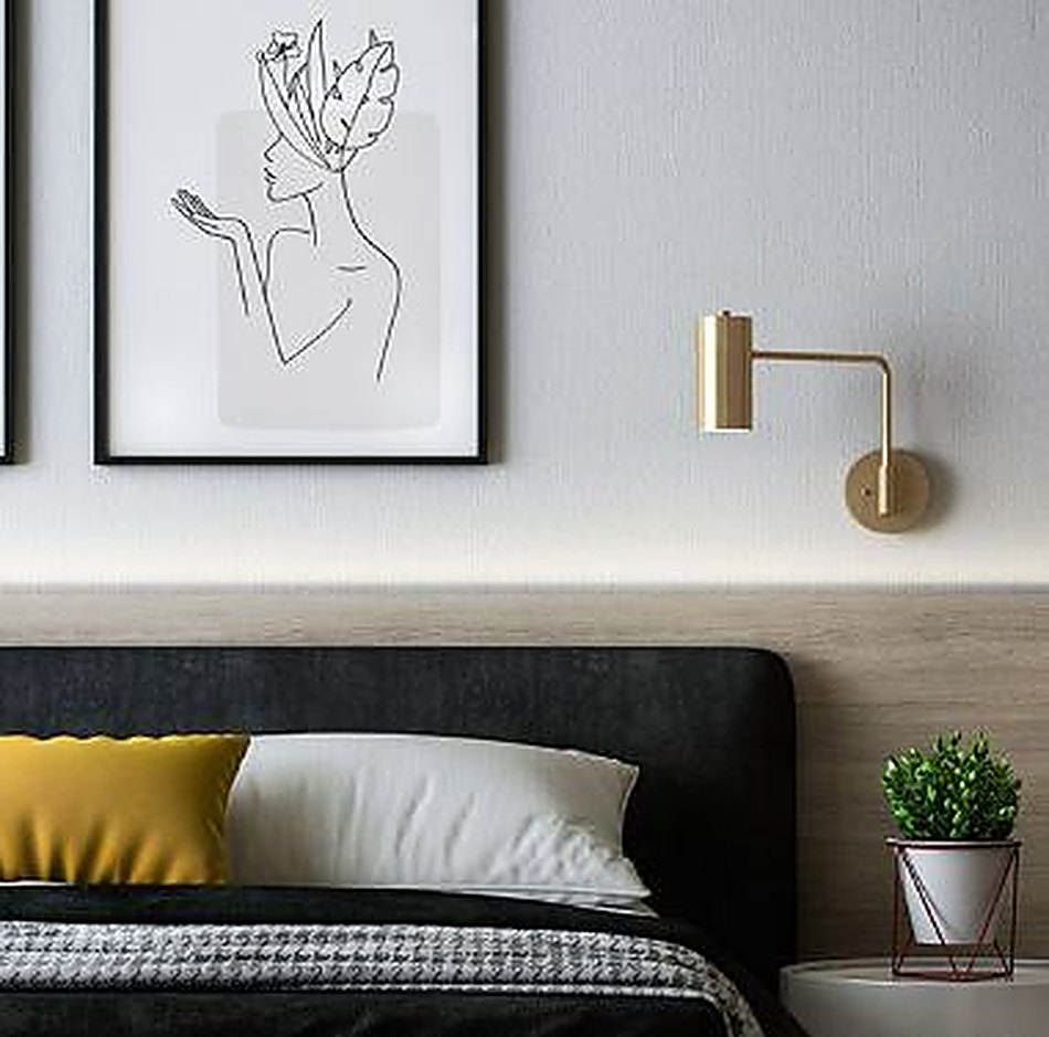 A slim brass wall sconce beside a framed line drawing