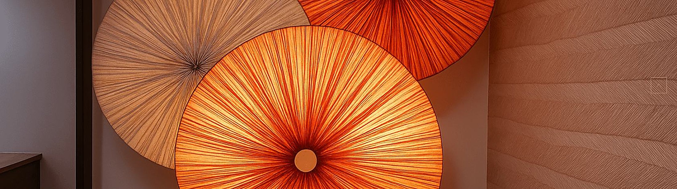 Pleated fan-form wall fixtures in graduated orange tones