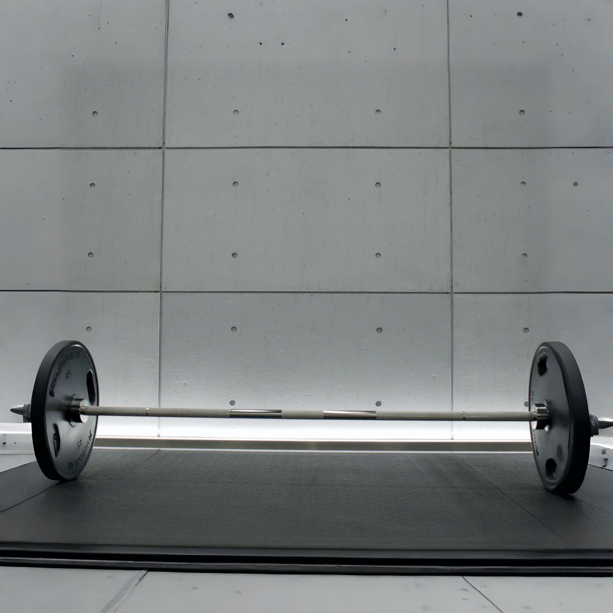 A barbell on a platform against a concrete wall lit by a low LED line