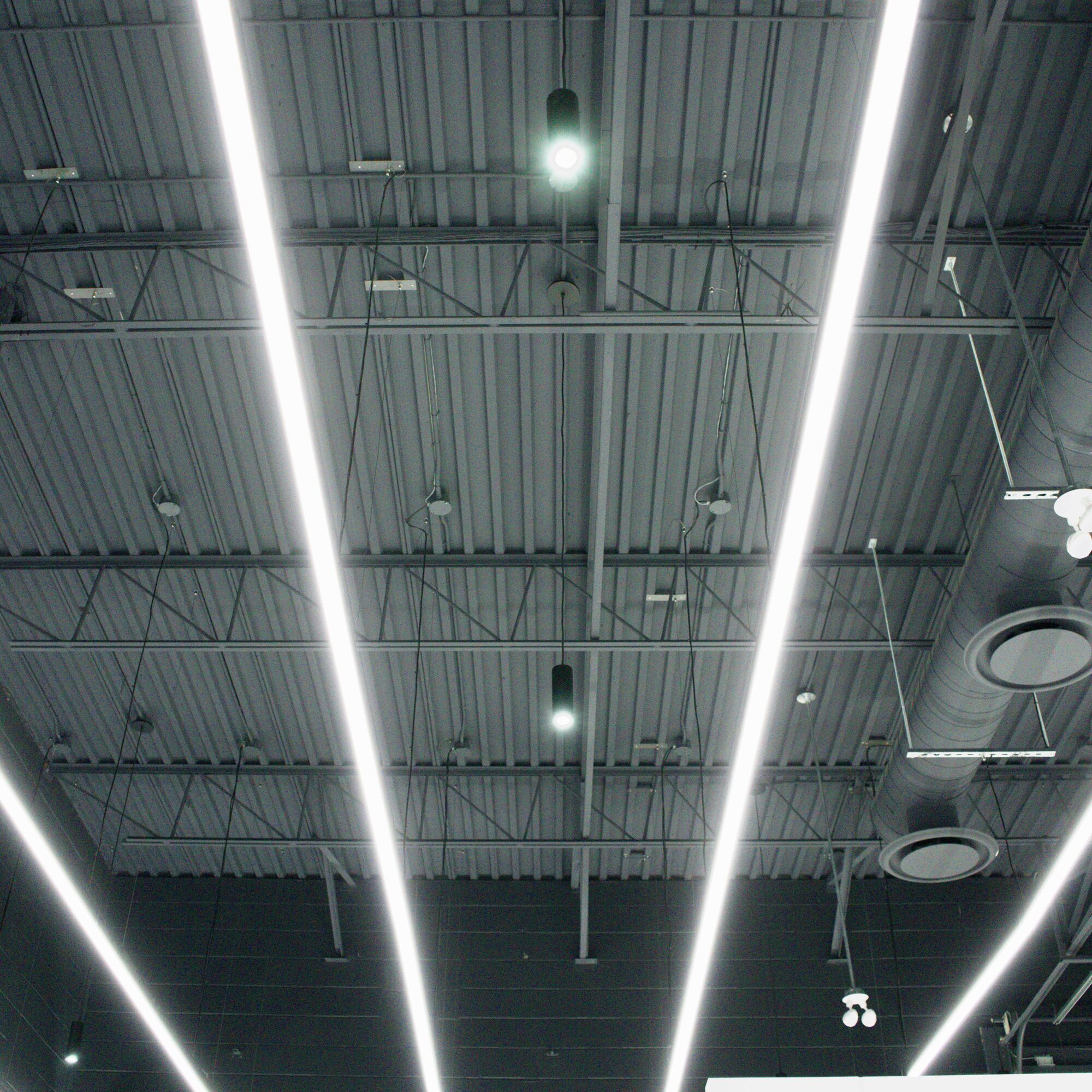 Parallel linear fixtures across the open-web joist ceiling