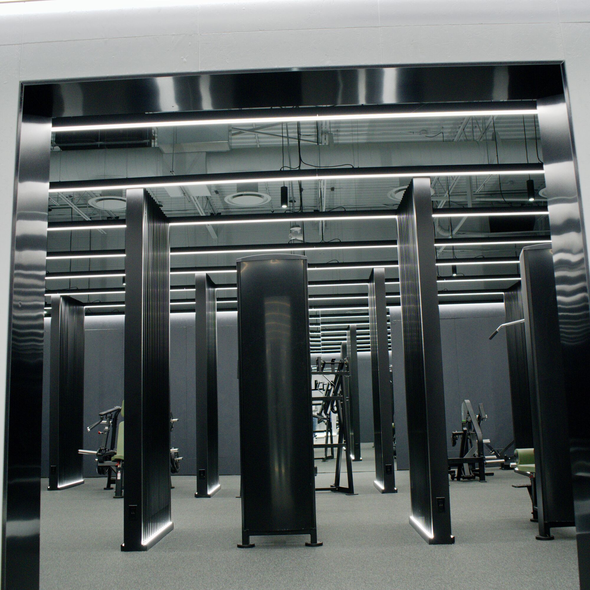 The gym floor framed by fluted black columns, with linear light runs overhead