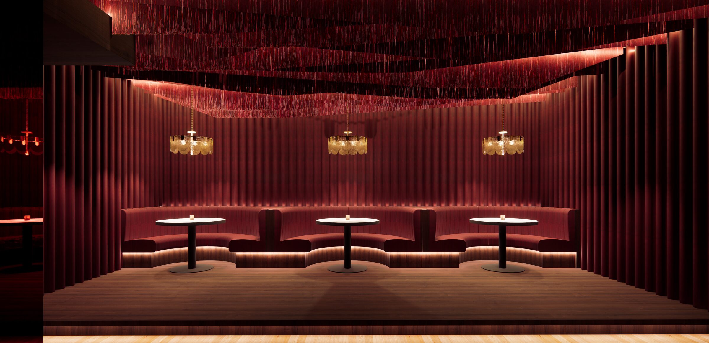 Red banquettes under a textured ceiling with brass pendants