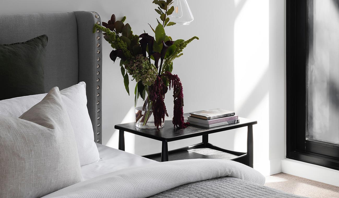 A bed with pillows and a table with flowers on it