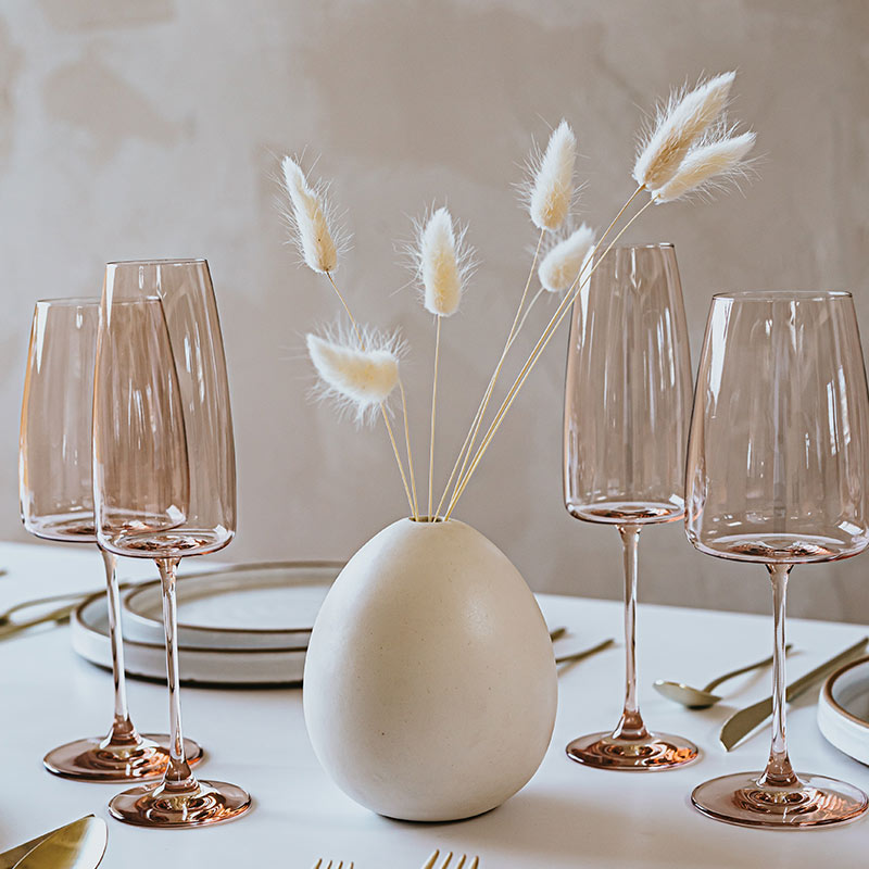 A table set with four glasses and a vase.