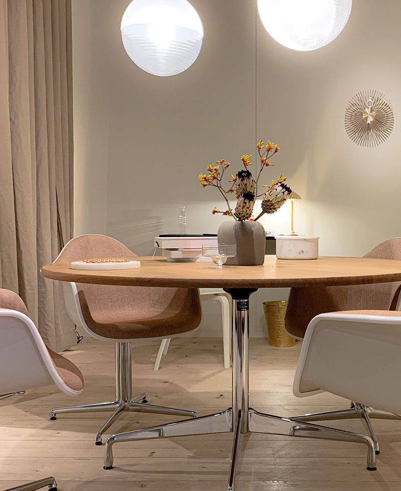 A dining room table with four chairs and a vase of flowers.