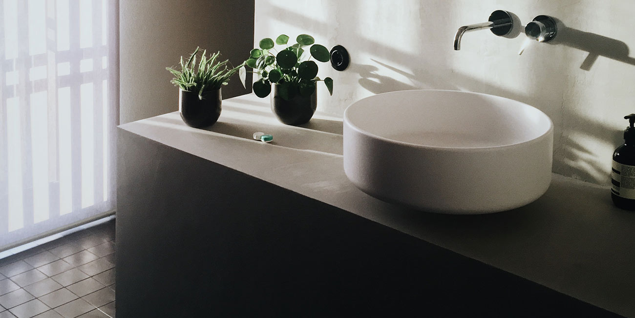 A bathroom sink with two plants on the counter.