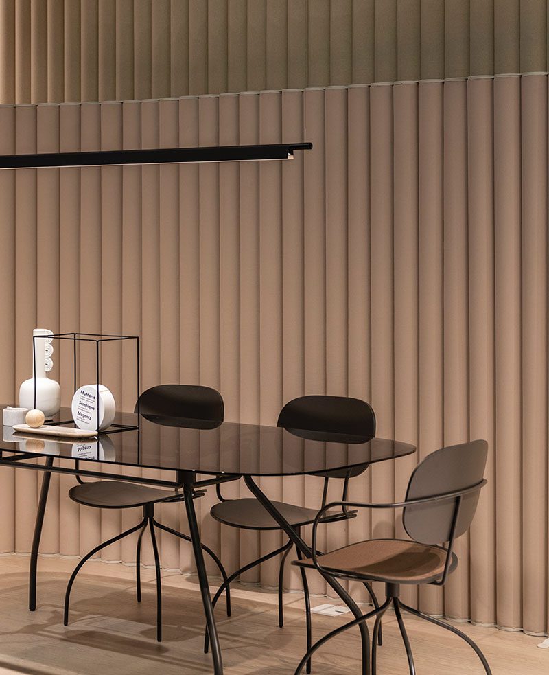 A table with four chairs and a clock on the wall.