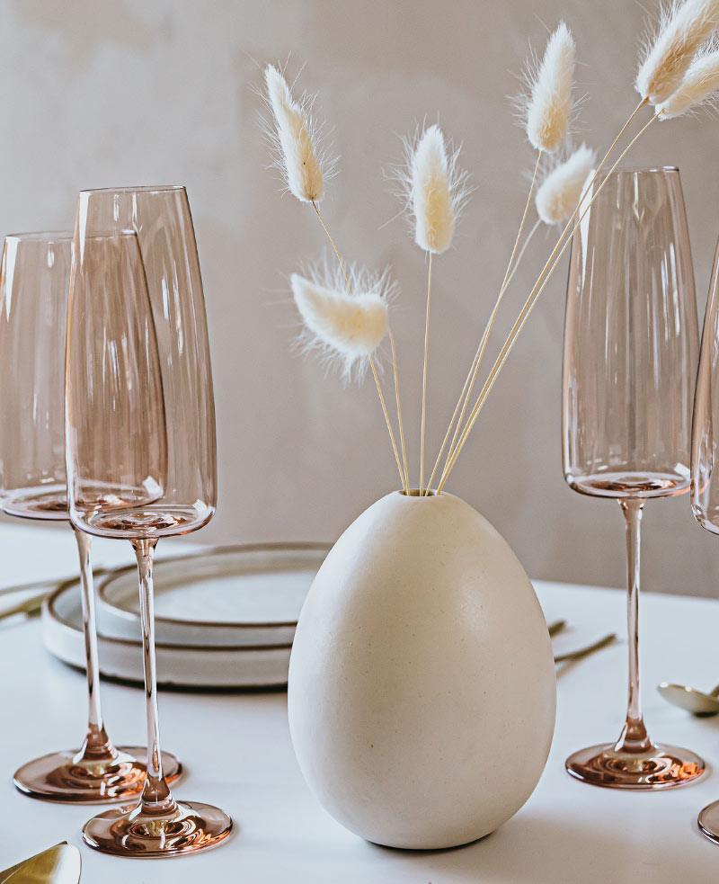 A table with wine glasses and a vase on it