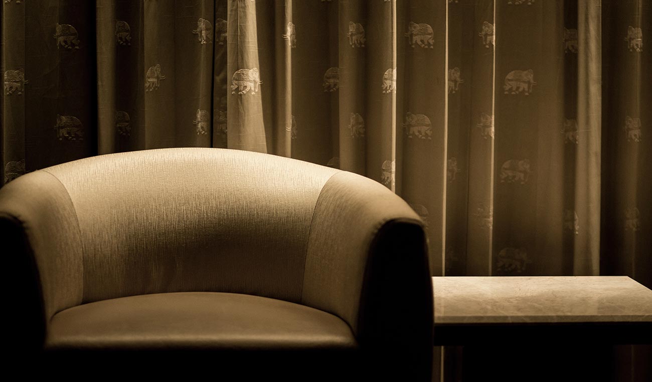 A chair and table in front of curtains.