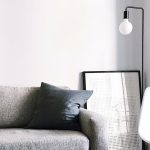 A couch with pillows and a lamp on the wall