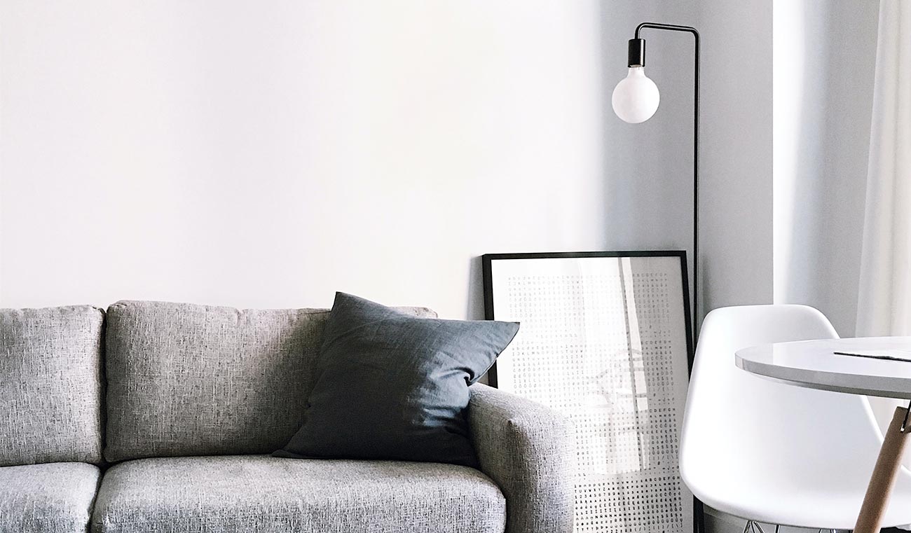 A couch with pillows and a lamp on the wall