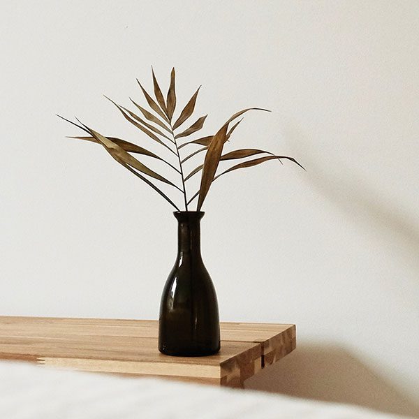 A black vase with some brown leaves in it