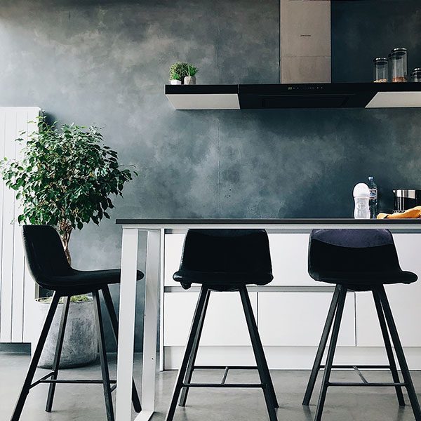 A kitchen with three black chairs and a table